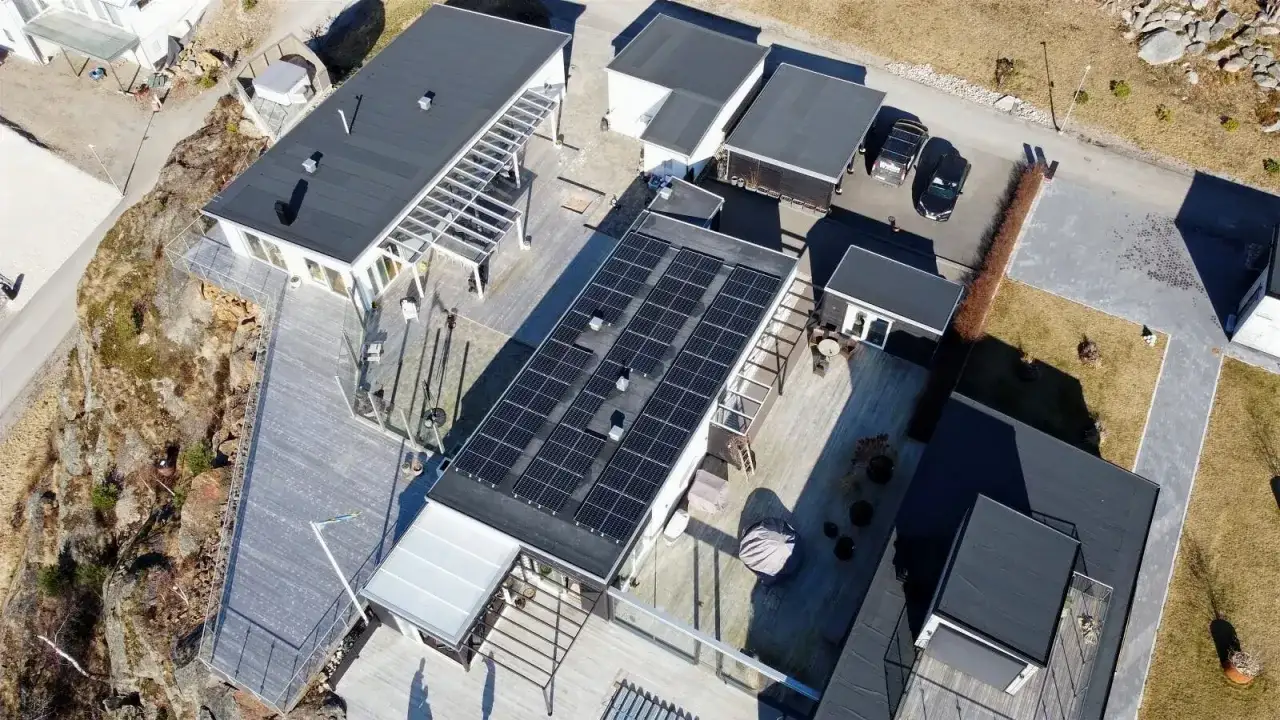 Moderna hus med stora tr&auml;d&auml;ck och en imponerande takinstallation av **denim solar**-paneler som f&aring;ngar solens energi.