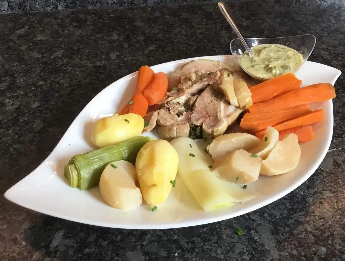 Tête de veau savoureuse servie avec des légumes racines et une sauce crémeuse.