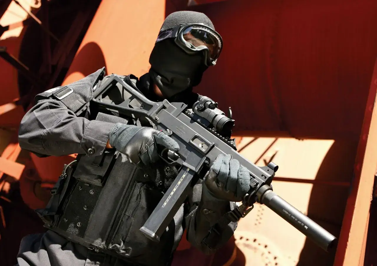 Un op&eacute;rateur en tenue noire, masque et lunettes, tient un HK UMP 9. Fiche technique d&eacute;taill&eacute;e de cette arme compacte.