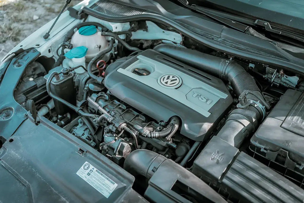 Silnik 2.0 TSI Volkswagena, widok z góry. Widoczne elementy układu dolotowego i osłona silnika z logo producenta.