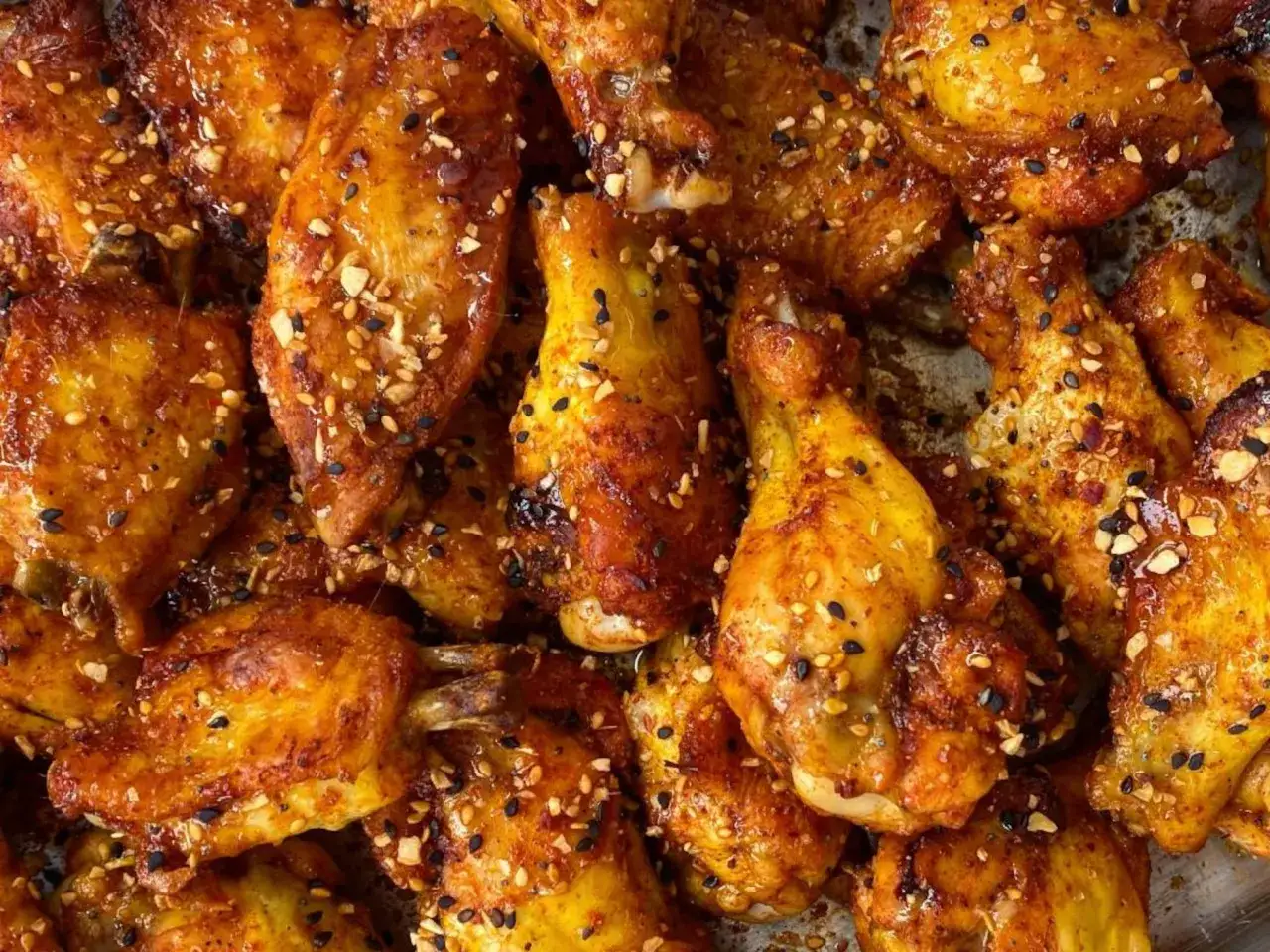 Alitas de pollo al horno jugosas, doradas y cubiertas con semillas de sésamo y especias. ¡Un festín irresistible!