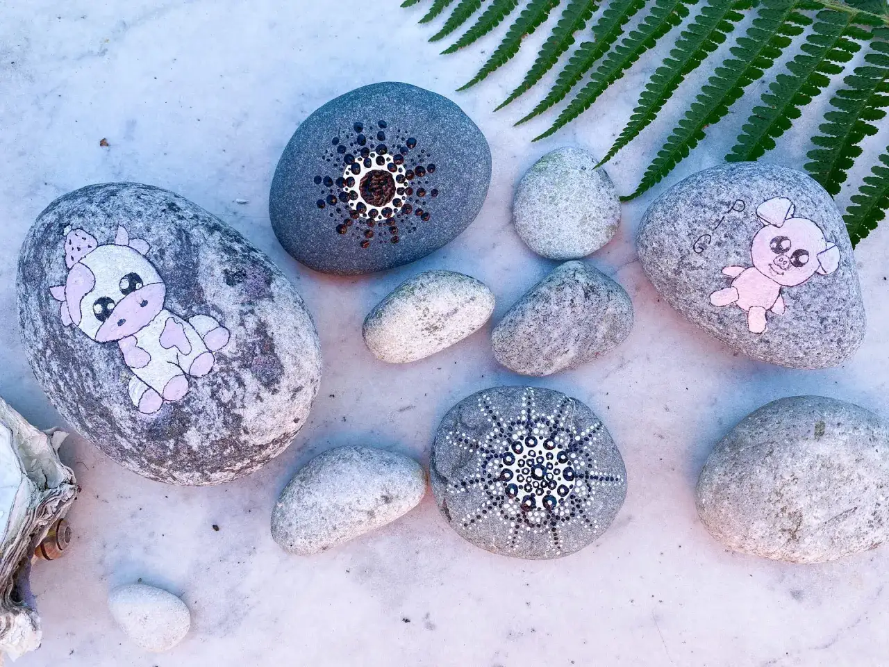 Söta djur och mandalas målade på stenar. En ko, en gris och två mönster som visar hur man kan måla på sten.