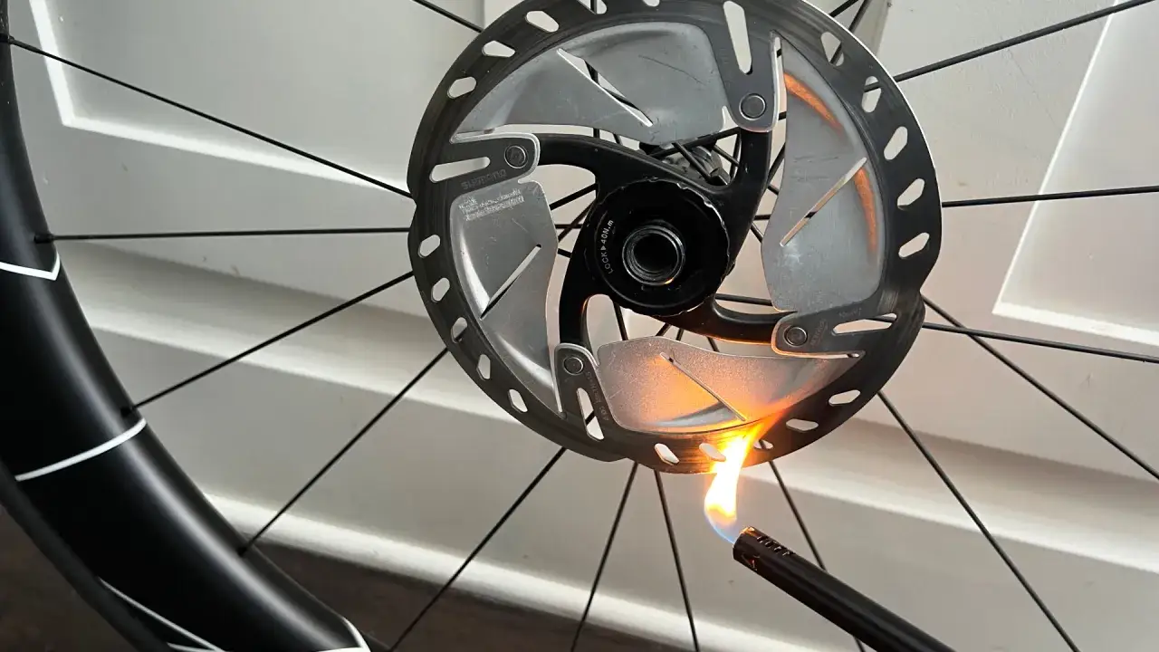 A lighter flame heats a bicycle's disc brake rotor. This is not how you get better juice brakes.