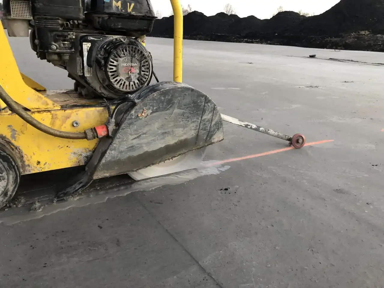 Cięcie betonu z użyciem wody. Maszyna z tarczą tnącą i silnikiem Honda pracuje na placu budowy, tworząc mokry ślad. Czy beton przepuszcza wodę?