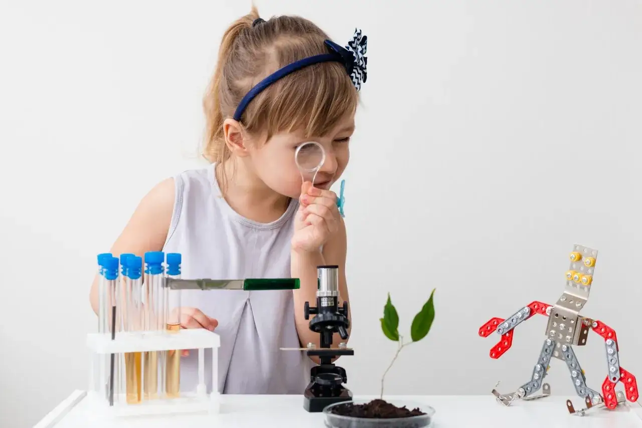 Ni&ntilde;a experimenta con inventos para ni&ntilde;os de 6 a 8 a&ntilde;os: microscopio, tubos de ensayo y un robot de metal.
