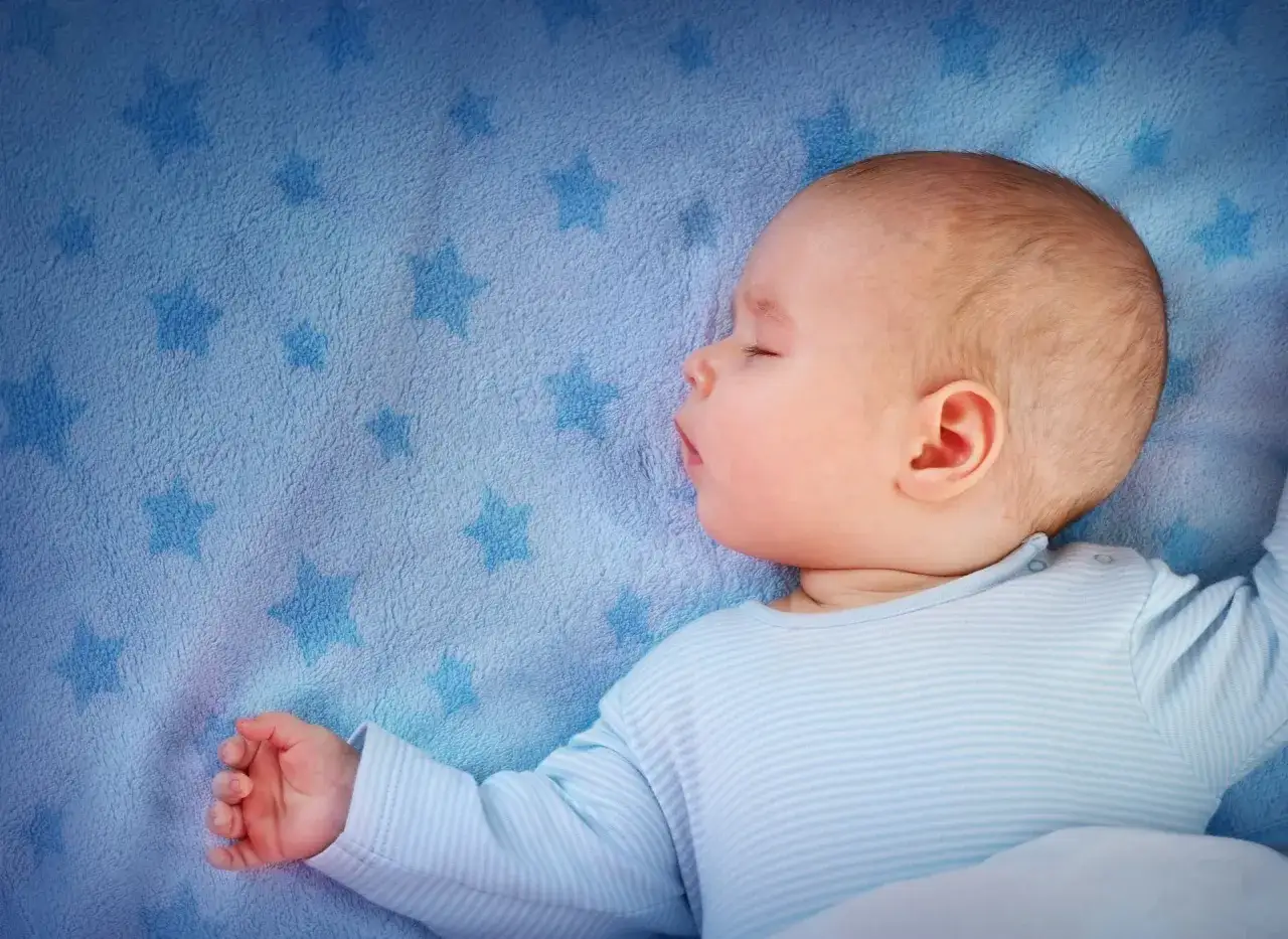 Dolce foto 9 mesi neonato dorme sereno su una coperta azzurra con stelline.
