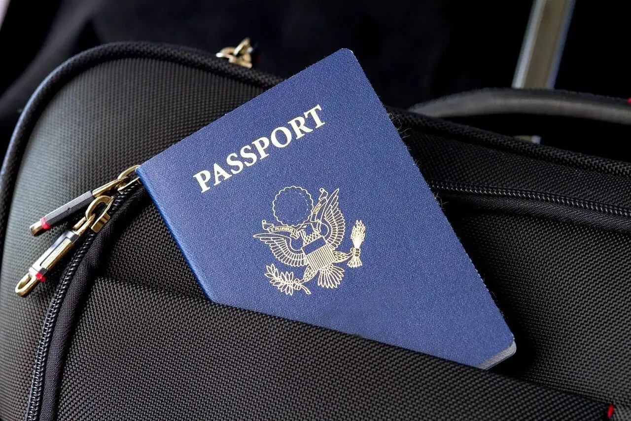 Niebieski paszport z godłem USA spoczywa na czarnej torbie podróżnej. Czas pomyśleć, kiedy wymienić paszport, by podróżować bez przeszkód.