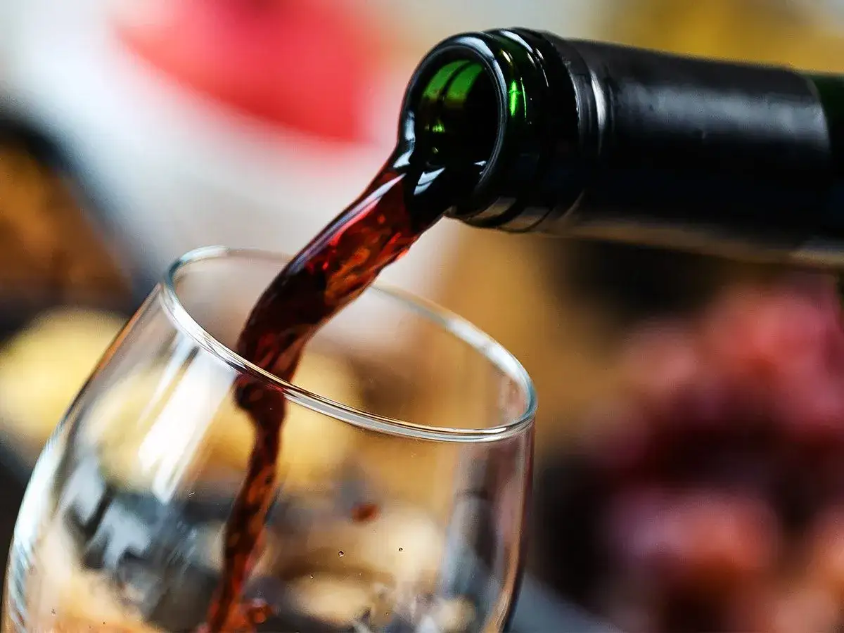 Czerwone wino nalewane do kieliszka. Metaliczny posmak w winie może być spowodowany błędami w produkcji.