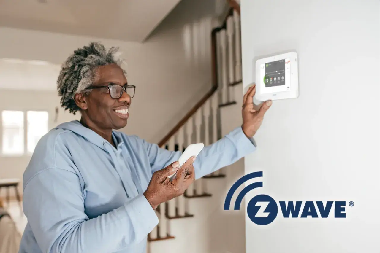 &Auml;ldre kvinna med mobiltelefon interagerar med en Verisure-panel, som styrs via Z-Wave-teknik f&ouml;r ett smart hem.