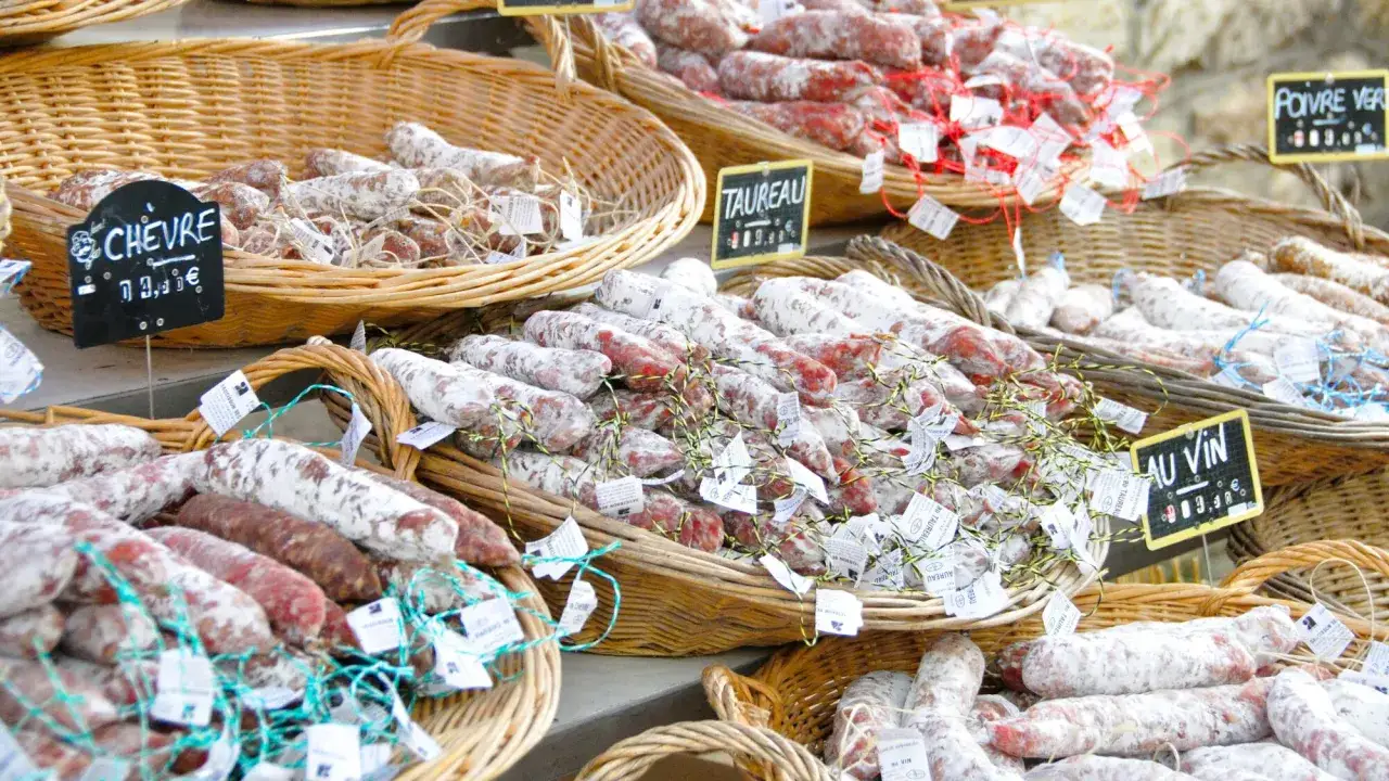 Des saucissons secs variés, exemples de produits du terroir, présentés en paniers. On distingue 