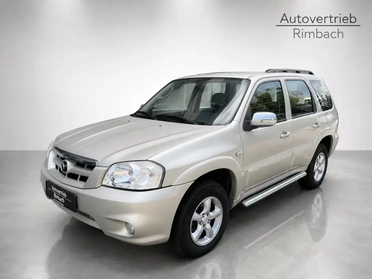 Srebrny Mazda Tribute z chromowanymi dodatkami i relingami dachowymi, gotowy na przygodę.