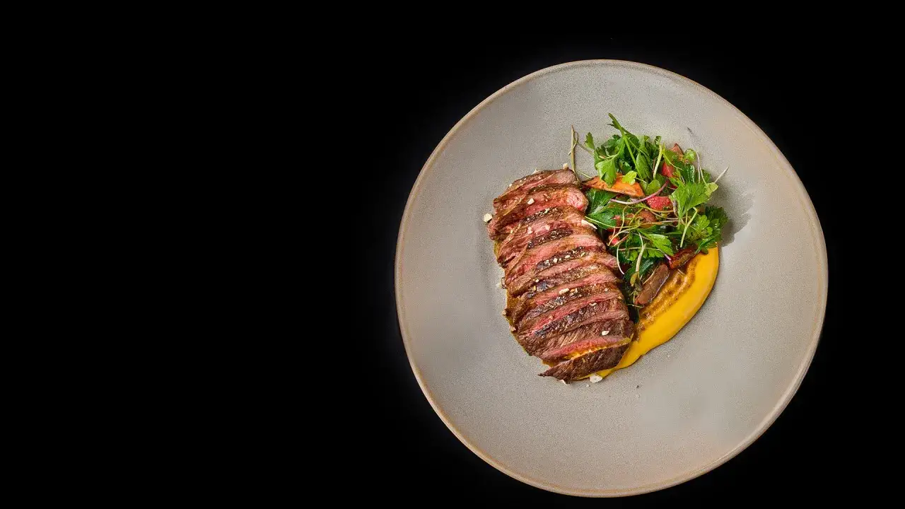 Tranches de rumsteak d'agneau juteux, servies avec une purée de courge et une salade fraîche.
