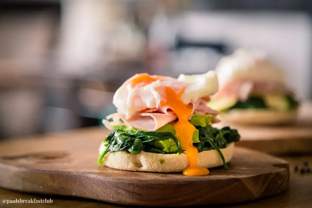 Ein k&ouml;stliches Egg Benedict mit Avocado, Spinat und zartem Schinken auf einem Muffin. Der fl&uuml;ssige Dotter flie&szlig;t verf&uuml;hrerisch &uuml;ber die Zutaten.