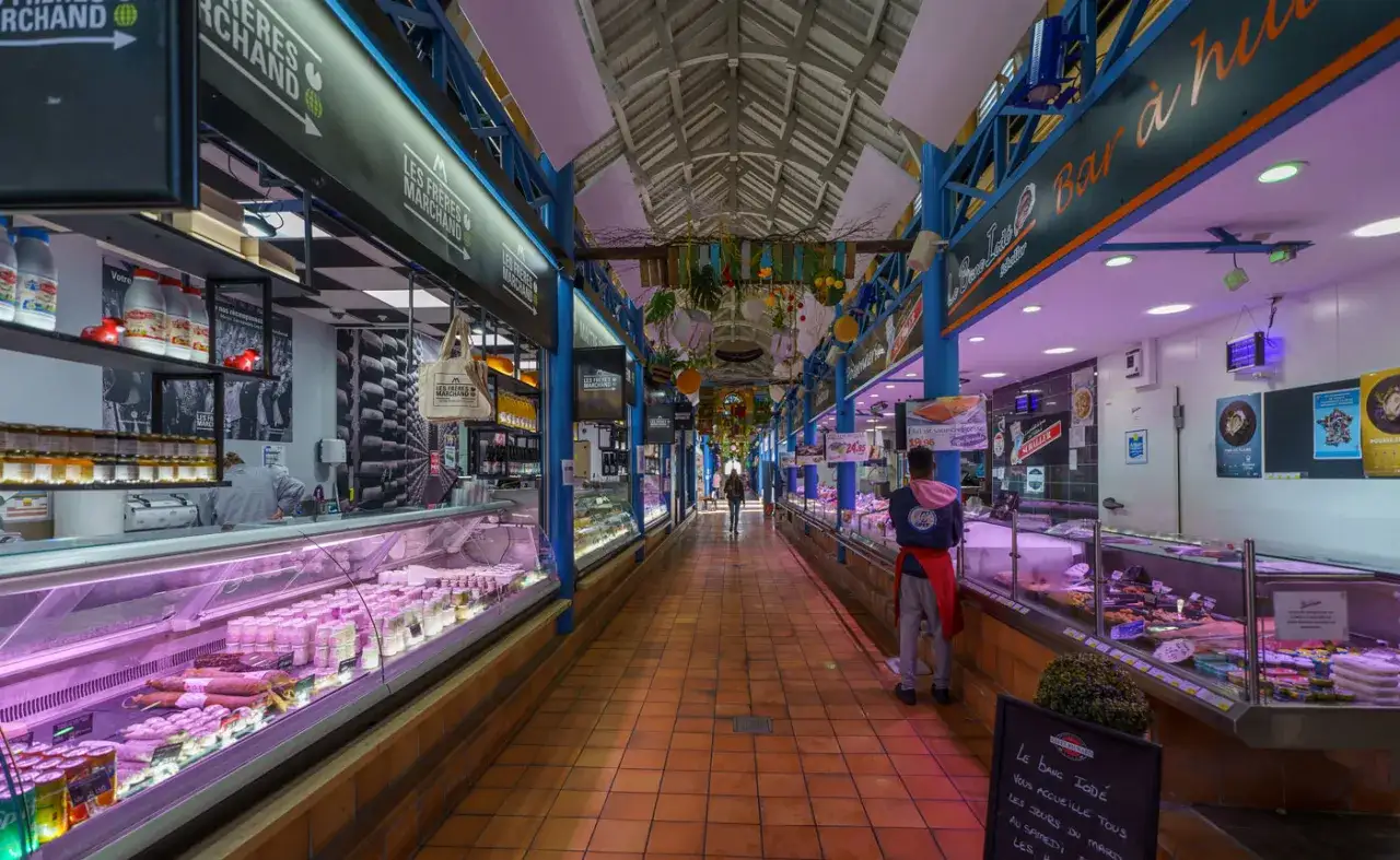 Allée d'un marché couvert à Metz, avec des étals de charcuterie et poissonnerie proposant des spécialités locales.