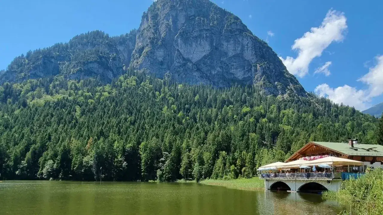 Ein **Geheimtipp Garmisch-Partenkirchen**: malerischer Bergsee mit Berghütte und Biergarten, umgeben von dichten Wäldern und imposanten Felsen.