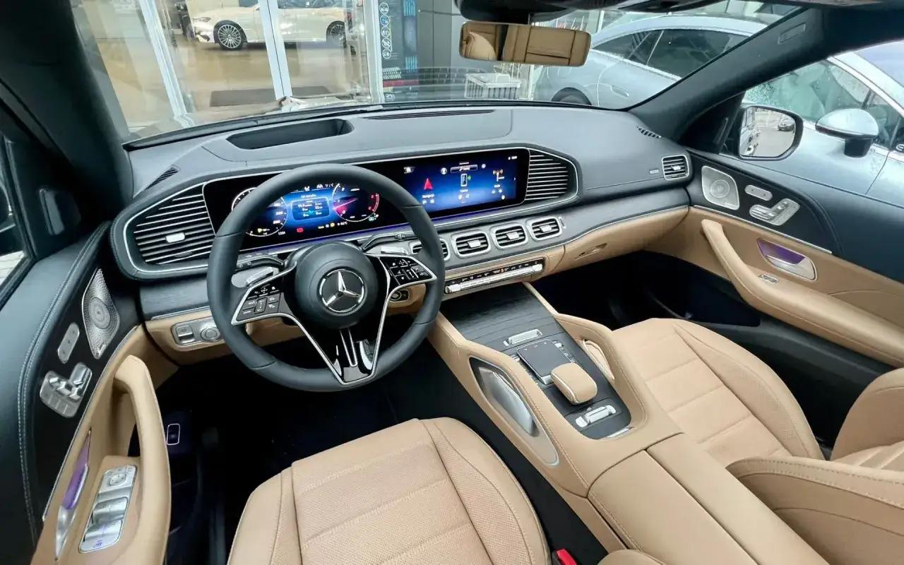 Wnętrze luksusowego Mercedesa GLE 450 z beżową tapicerką i nowoczesnym panelem cyfrowym.