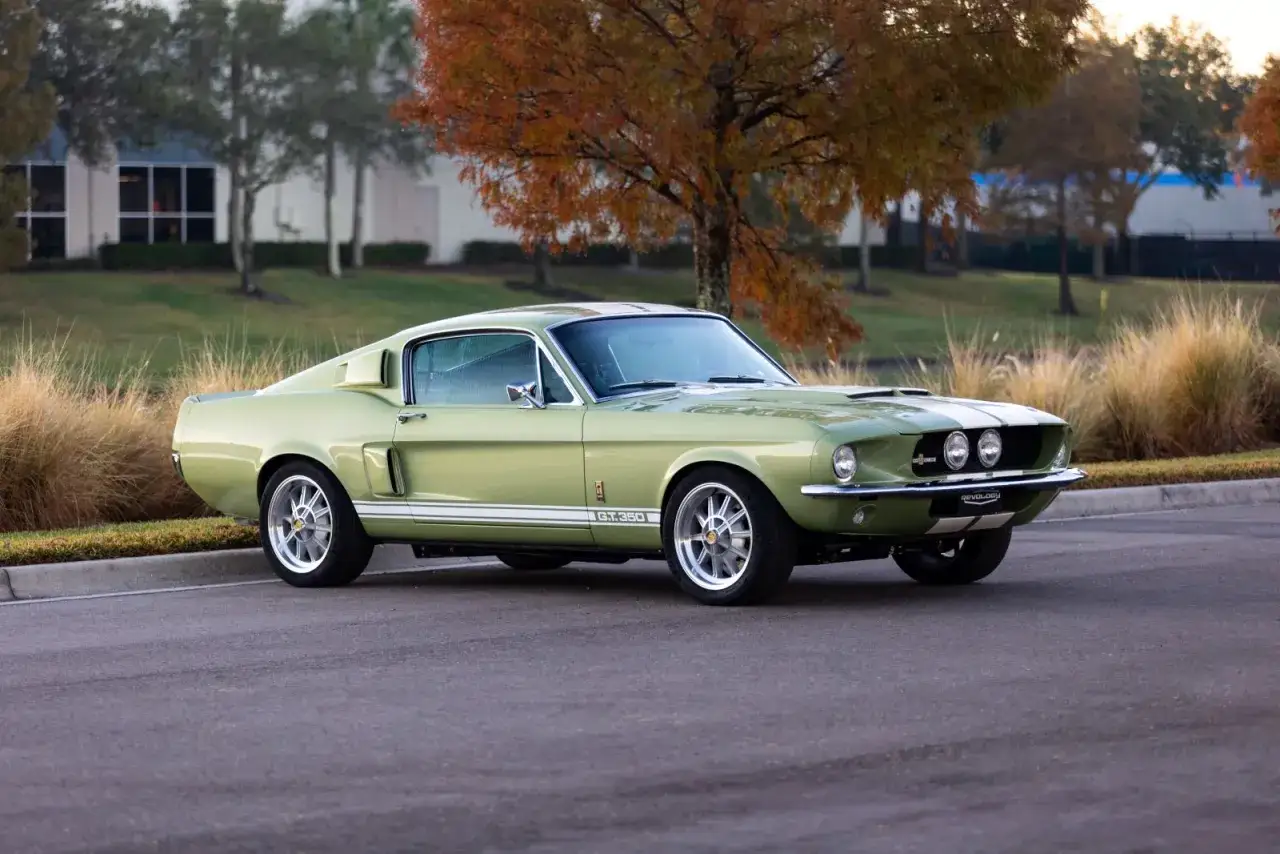 En ljusgrön Shelby GT350 med vita ränder står parkerad utomhus.