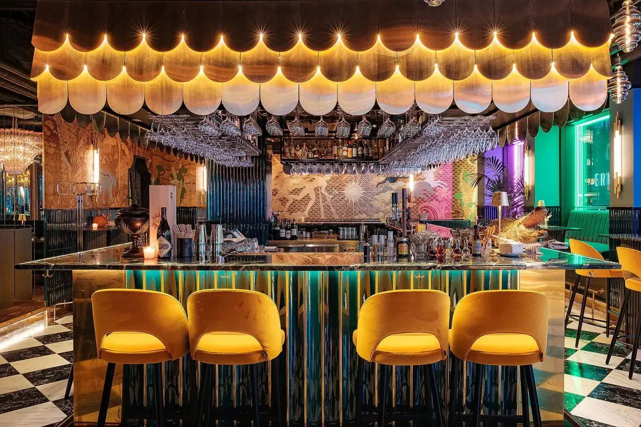 En mysig restaurang i Stockholm med en lyxig bar, gul sammetsklädda stolar och en unik inredning med konst och belysning.