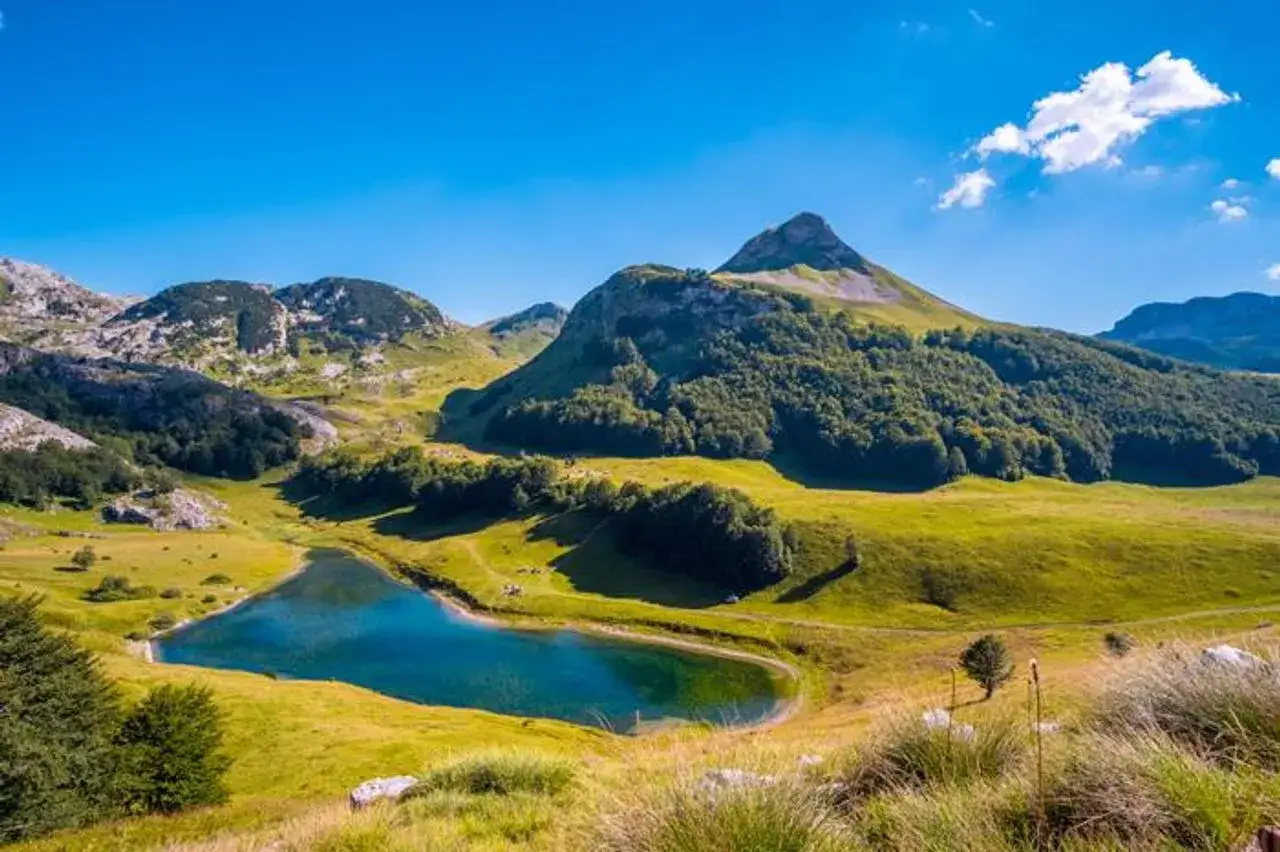 Atemberaubende bosnische Natur: Ein klarer blauer See spiegelt die gr&uuml;nen Berge und den Himmel wider.