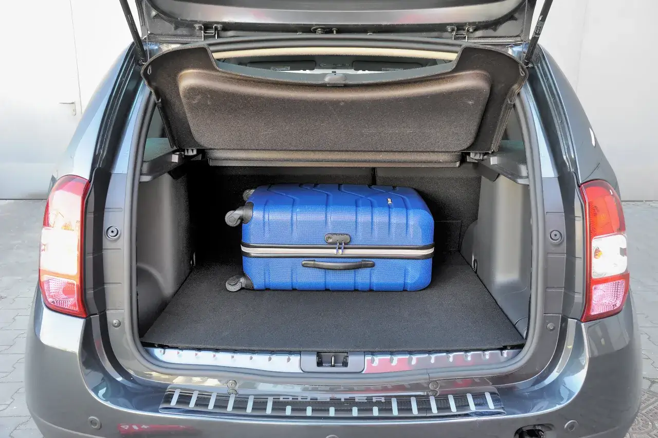 Błękitna walizka w bagażniku Dacia Logan MCV II, gotowa na podróż.
