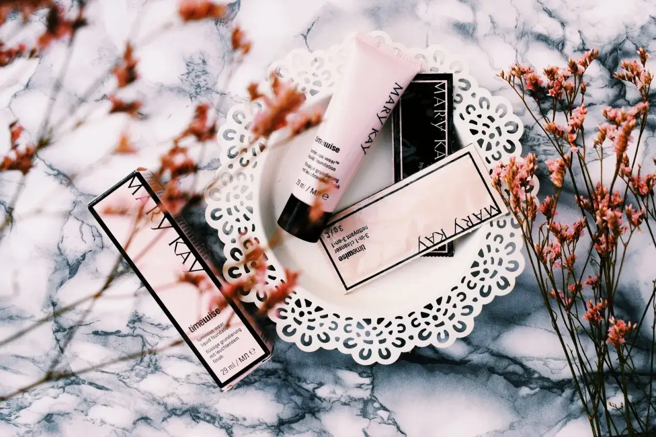 Mary Kay Timewise podkład rozświetlający i kosmetyki do pielęgnacji na marmurowym tle z kwiatami.