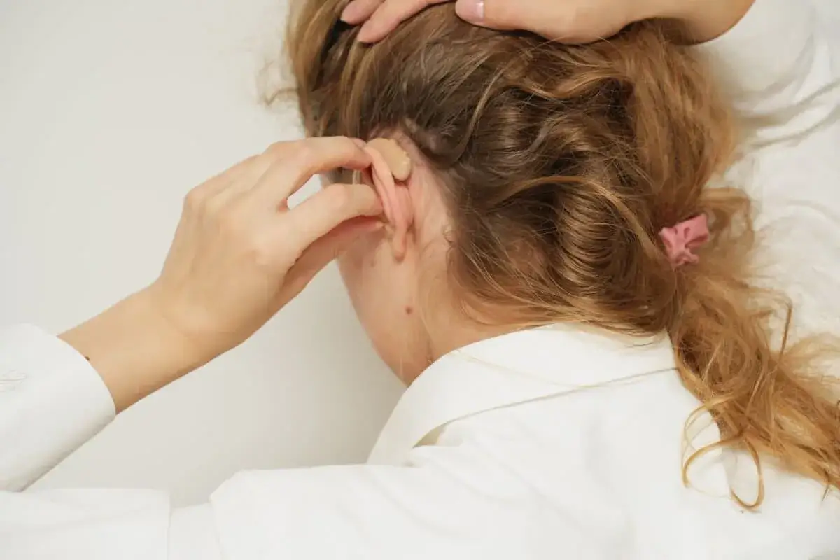 Frau mit H&ouml;rger&auml;t im Ohr, hofft auf Linderung von Tinnitus durch Vitamin B12.