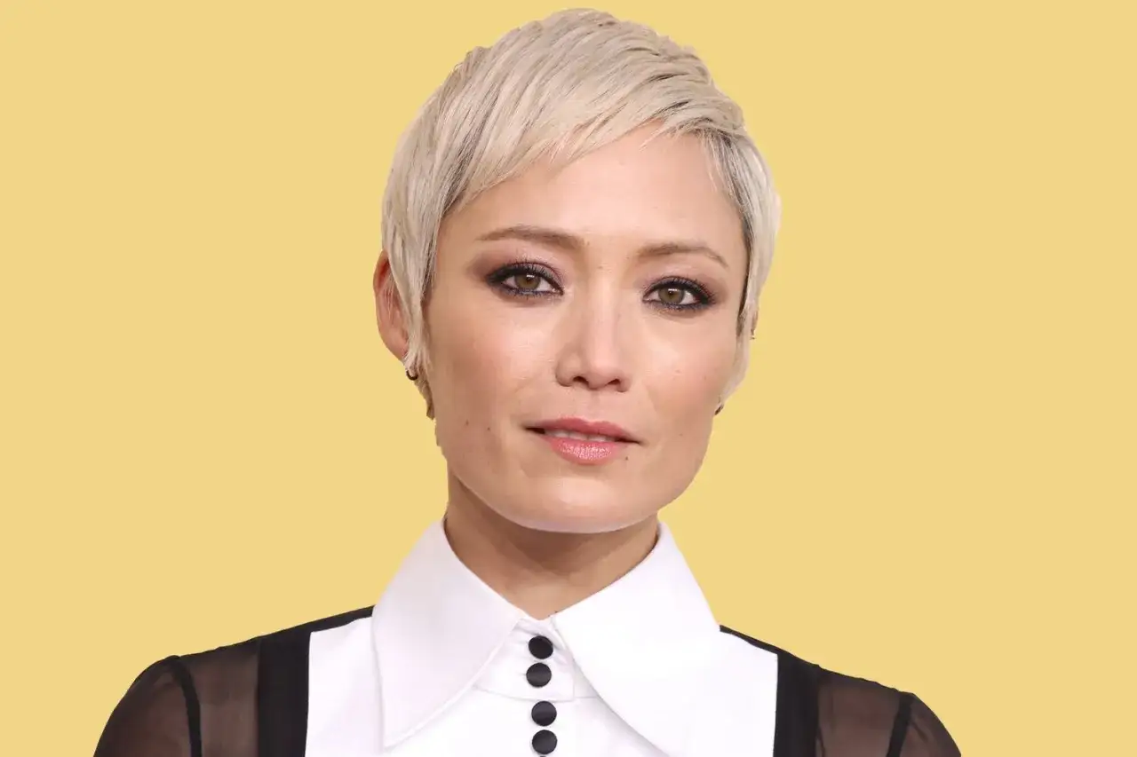 Mujer con un moderno flequillo corte pixie corto, cabello rubio platino, maquillaje dram&aacute;tico y blusa blanca con detalles negros.