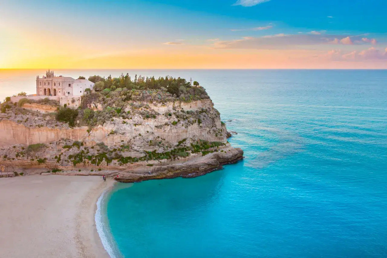 Sanctuary of Santa Maria dell'Isola a picco sul mare cristallino, un gioiello di Tropea e dintorni al tramonto.