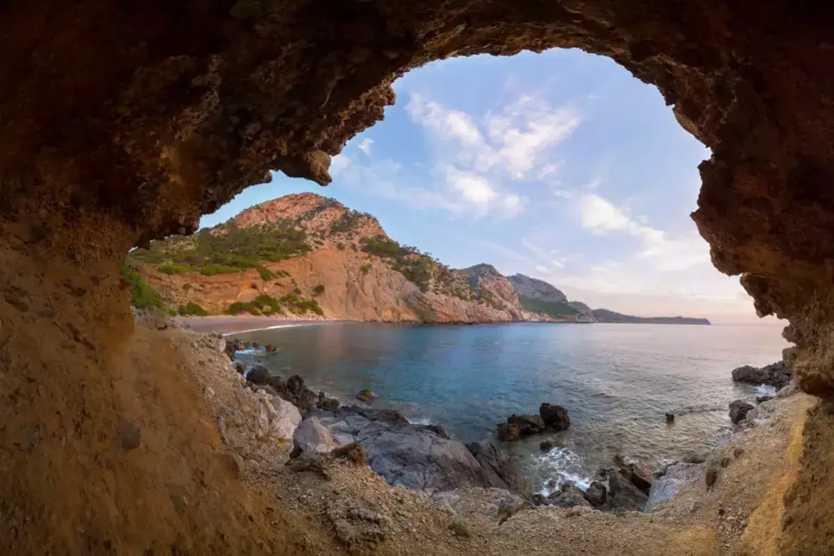 Blick aus einer H&ouml;hle auf eine Bucht mit Bergen und Meer im Osten Mallorcas.