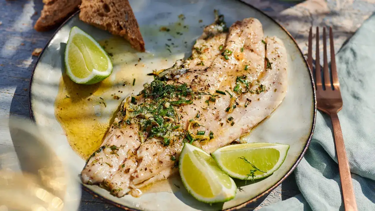 Gebratener Seebarsch mit Kr&auml;utern und Limette, ein Gericht, das den frischen Geschmack des Meeres einf&auml;ngt. Dazu knuspriges Brot.