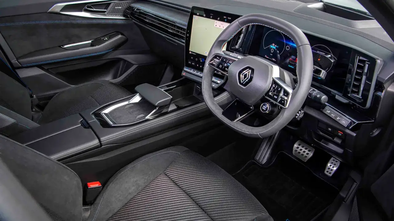 Interiörbild från en Renault Austral testkörning. Modern instrumentpanel med stor pekskärm och digital förardisplay. Blå sömmar på säten och dörrsidor.
