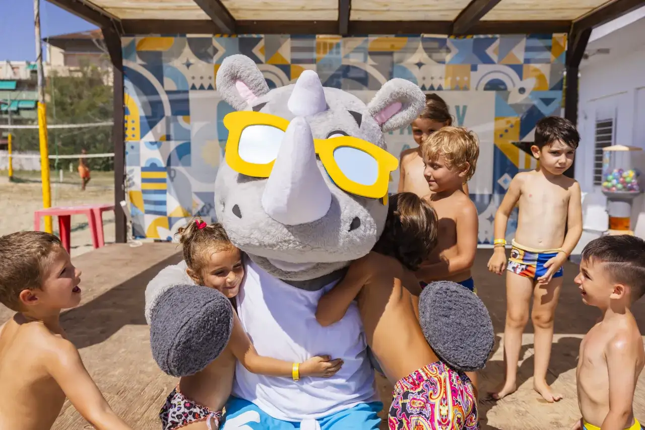 Bambini abbracciano un simpatico rinoceronte con occhiali da sole, un momento di gioia al brora family village.