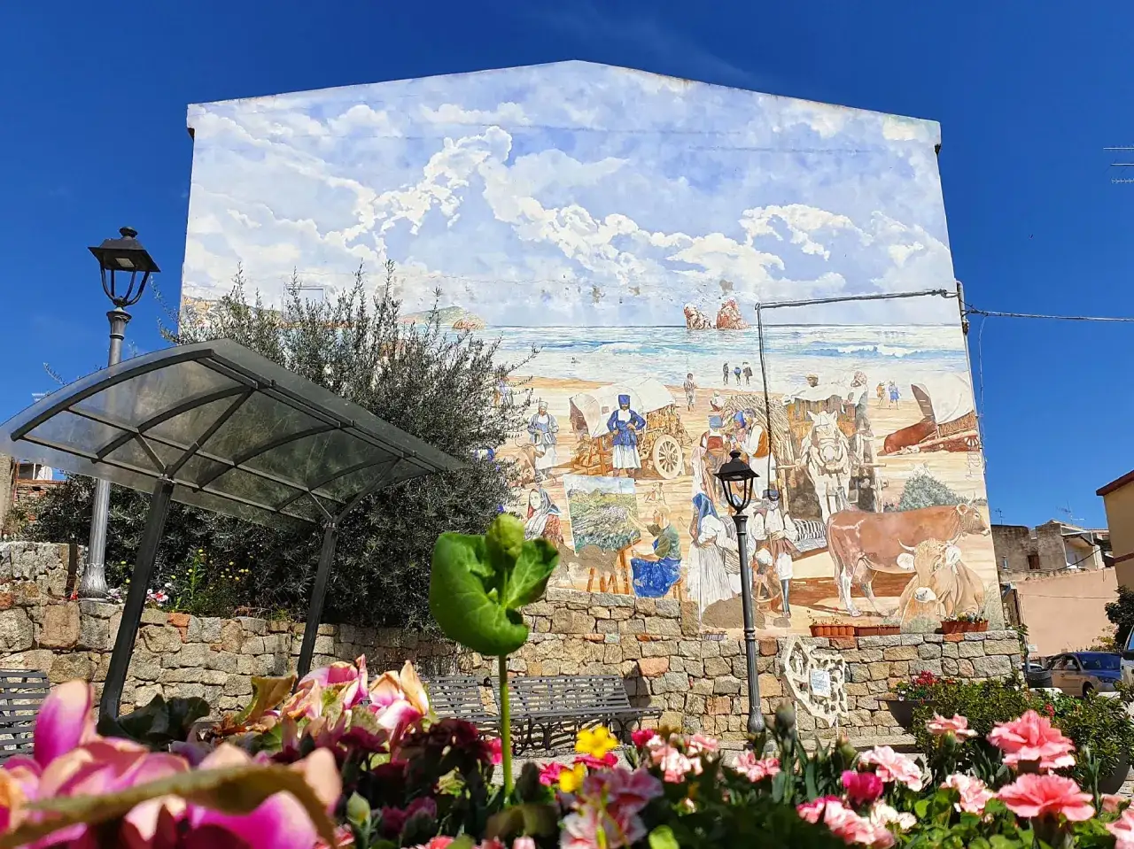Un murale a Loceri, Sardegna, raffigura scene di vita marina e rurale con personaggi in abiti tradizionali e animali.