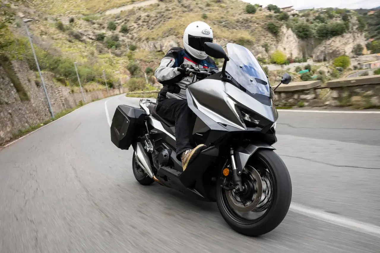 Motociclista en Honda Forza 750, explorando curvas en carretera. La velocidad máxima de este scooter es impresionante.