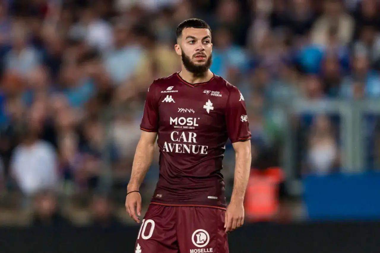 Georges Mikautadze w bordowej koszulce FC Metz, z numerem 10 na spodenkach, na tle trybun stadionu.