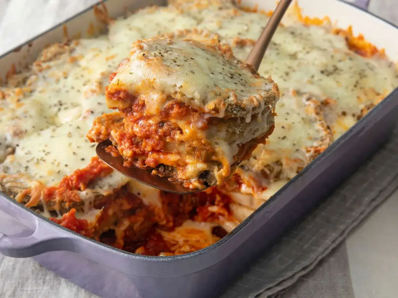Una porción generosa de berenjenas a la parmesana, con capas de berenjena, salsa de tomate y queso derretido, lista para ser disfrutada.