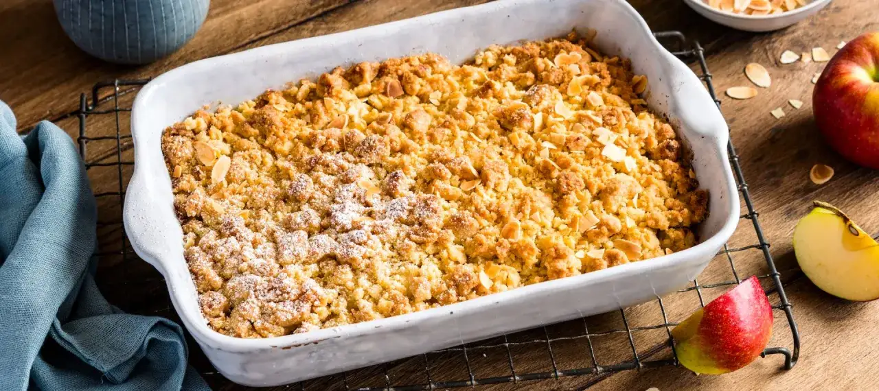 Goldbrauner Apfel Crumble mit Mandelblättchen, frisch aus dem Ofen, duftet verlockend.