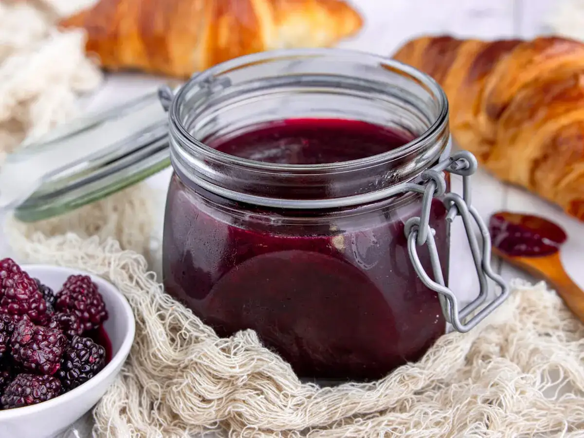 Glas mit Brombeergelee, frische Brombeeren und Croissants. Verschiedene Brombeergelee Varianten für den Frühstückstisch.