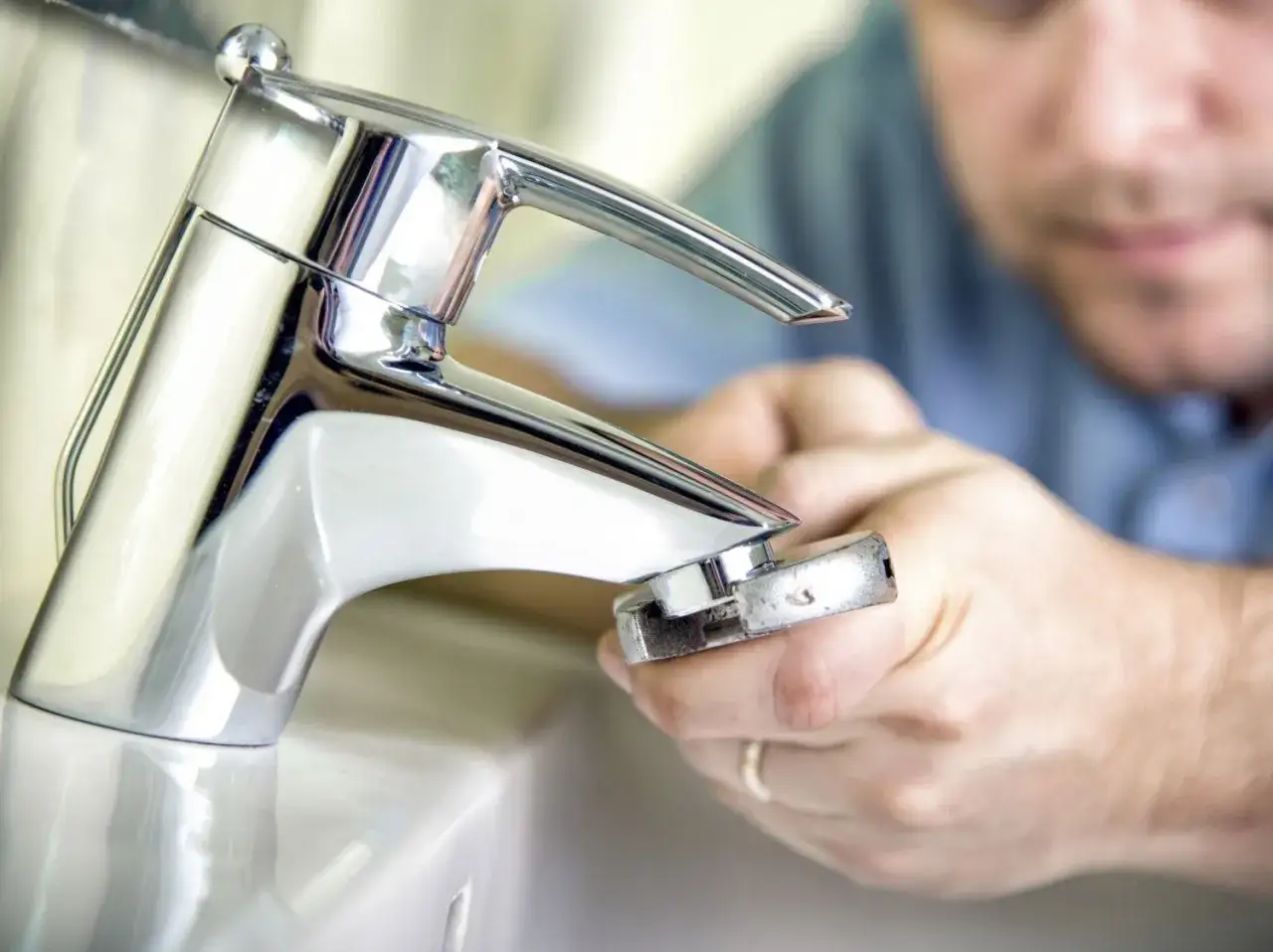 Un plombier répare un robinet qui fuit. L'eau goutte, mais il est sur le point de résoudre le problème.