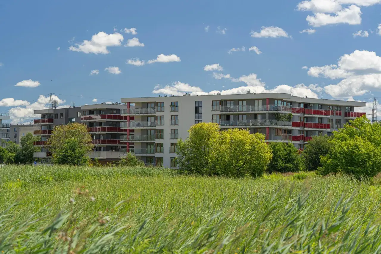 Nowoczesne bloki mieszkalne z balkonami, otoczone zielenią. Czy sekrety certyfikatów energetycznych A+ wpływają na cenę 