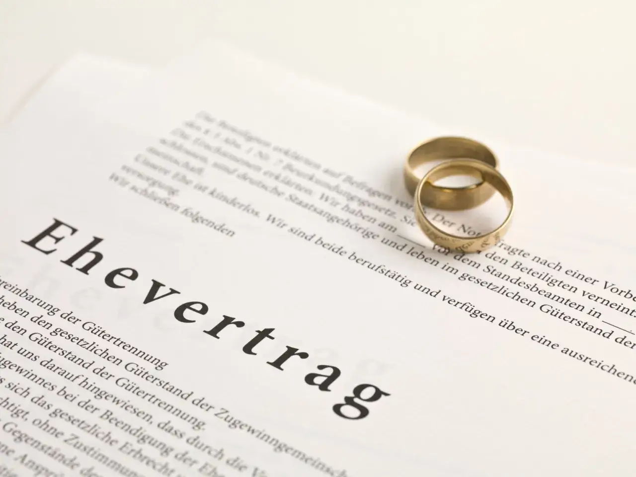 Zwei goldene Ringe liegen auf einem Ehevertrag. Der Text thematisiert die Aufhebung des Ehevertrags ohne Notar.