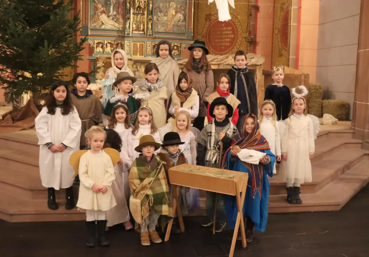Kinder in historischen Kostümen stellen eine Weihnachtsszene dar, die an Weihnachten im Mittelalter erinnert.