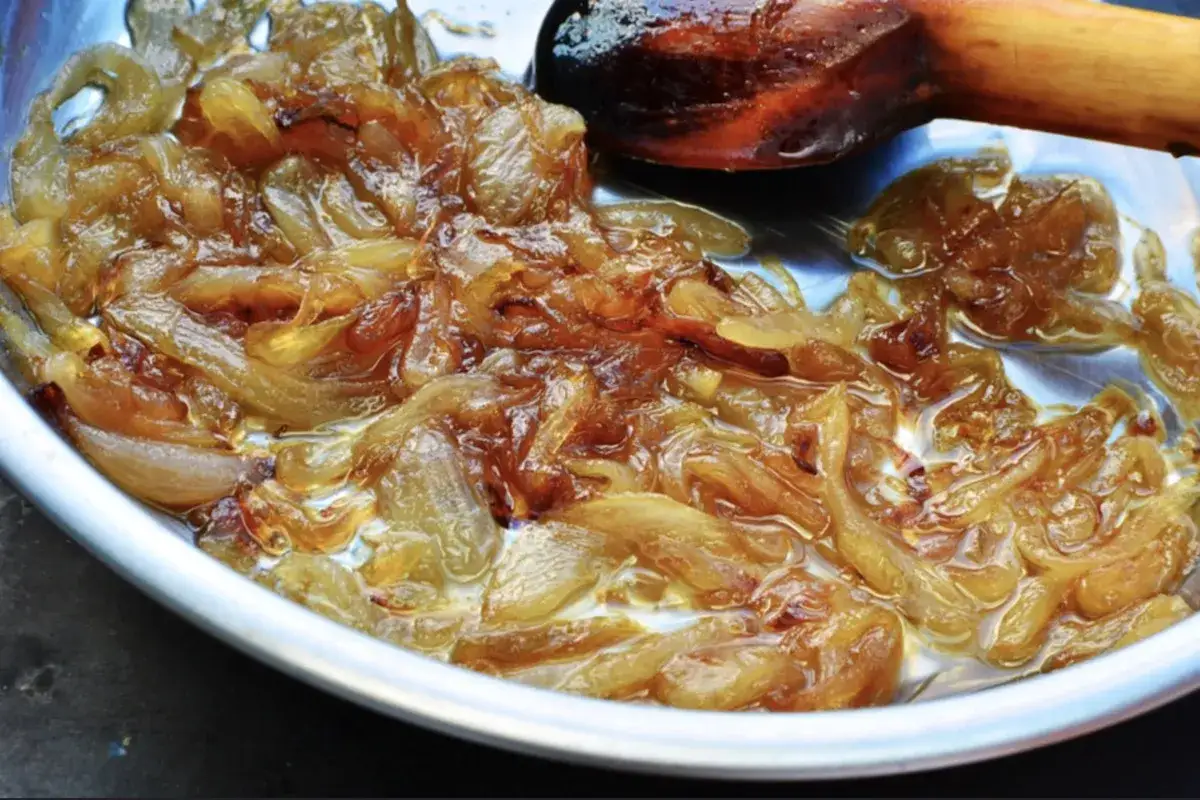 Oignons caramélisés dorés et fondants dans une poêle, prêts à sublimer un plat.