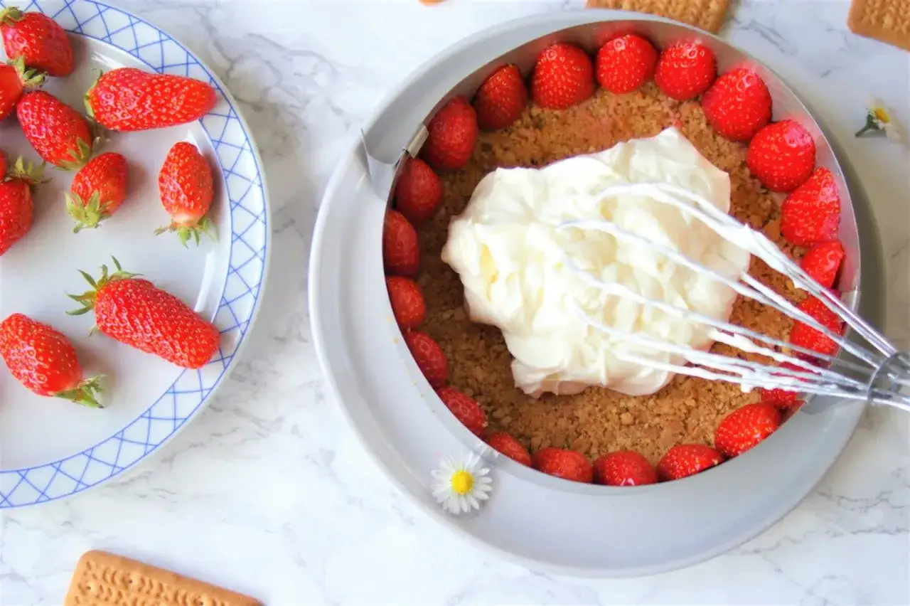 Pr&eacute;paration d'une recette fraisier mascarpone : fraises fra&icirc;ches, cr&egrave;me onctueuse et biscuits &eacute;miett&eacute;s dans un cercle &agrave; p&acirc;tisserie.