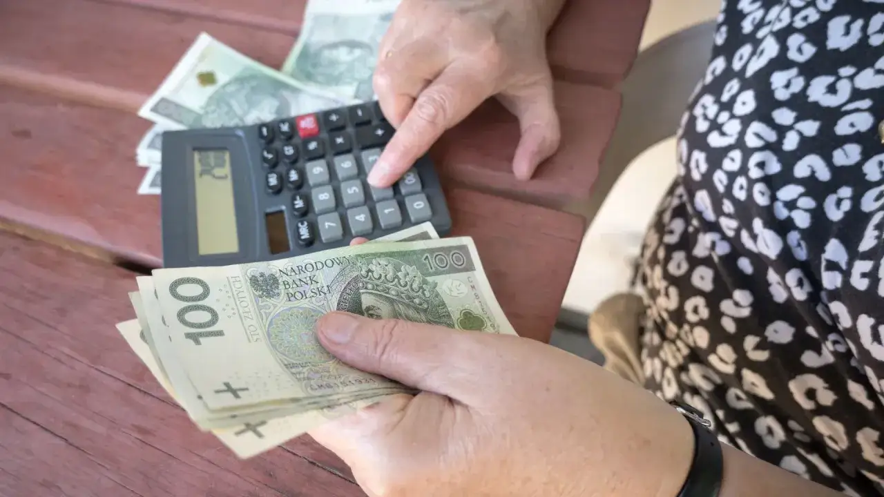 Ręce liczą pieniądze i kalkulator. Zastanawiasz się, ile wzrośnie emerytura z OFE po 65 roku życia?