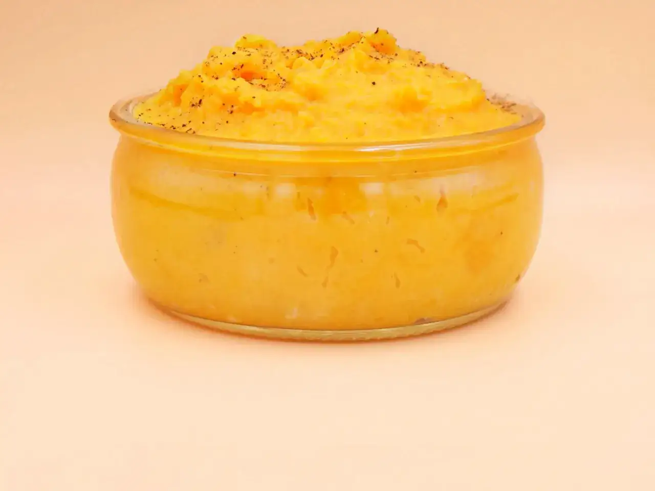 Pyszne, kremowe puree z batata w szklanym naczyniu, posypane świeżo mielonym pieprzem. Idealne jako dodatek do obiadu.