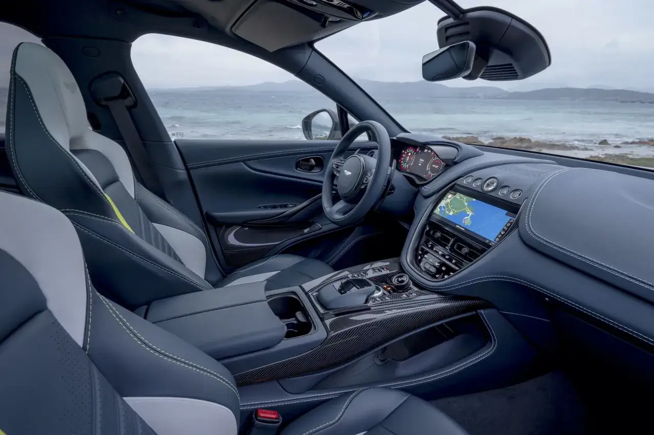 Wnętrze Aston Martin DBX 707 z widokiem na morze. Skórzane fotele, cyfrowe zegary i nawigacja.