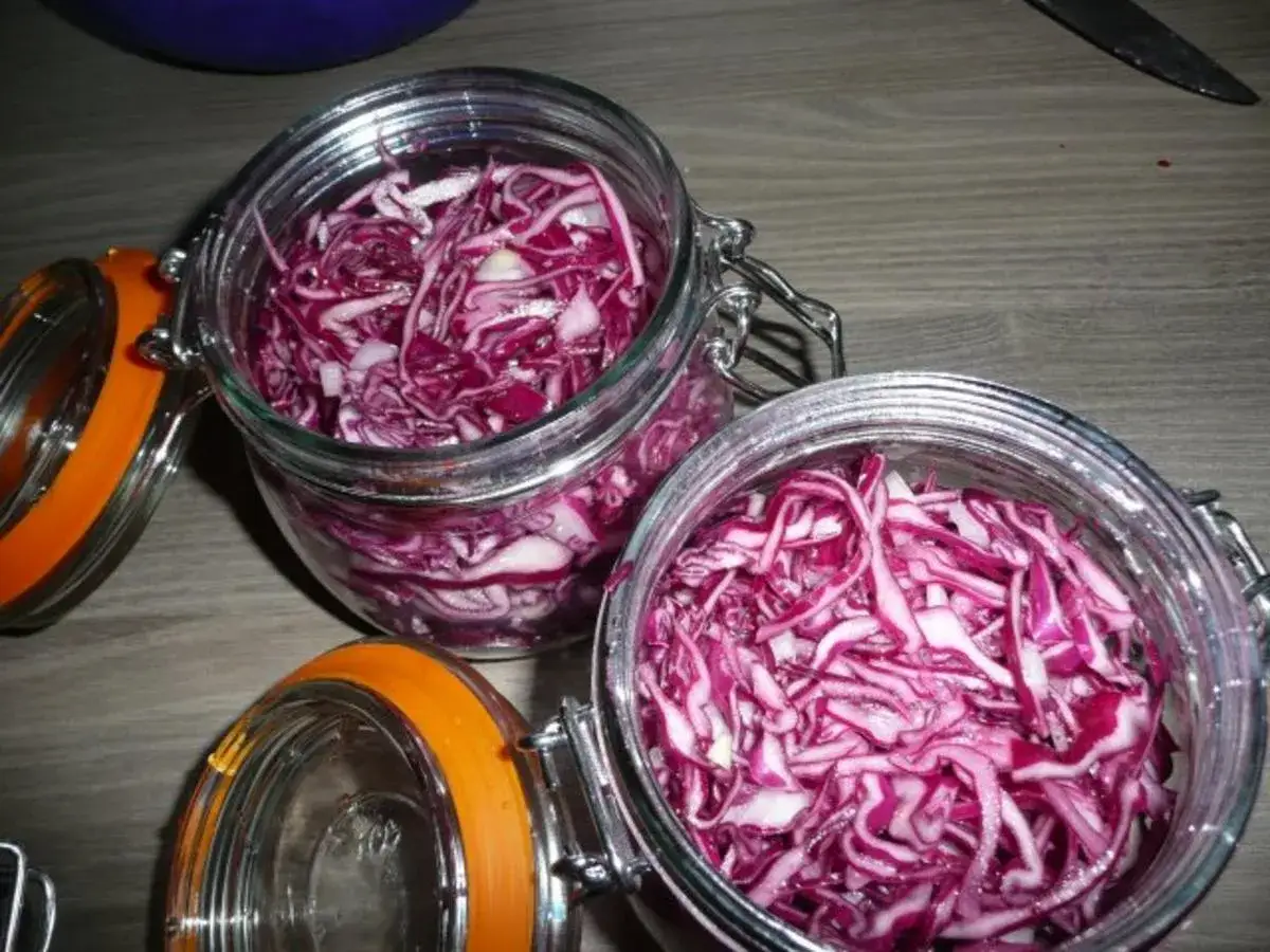 Zwei Gl&auml;ser mit fein geschnittenem Rotkraut, bereit zum Rotkraut einkochen. Die orangefarbenen Deckel liegen daneben.