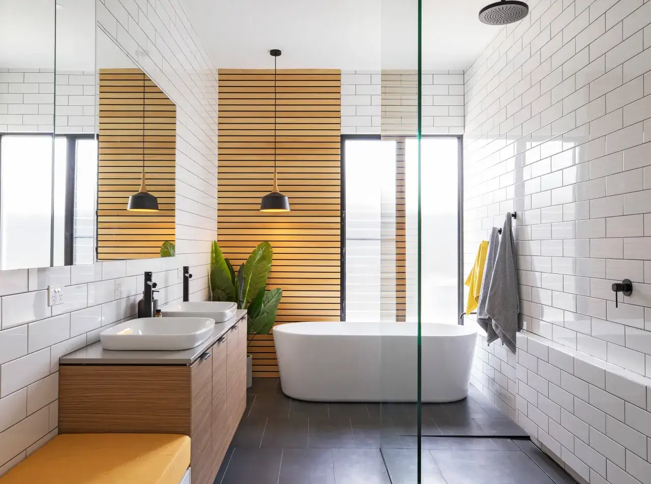 Salle de bain moderne avec baignoire îlot, double vasque, murs carrelés blancs et lambris bois. La largeur baignoire standard est bien mise en valeur.