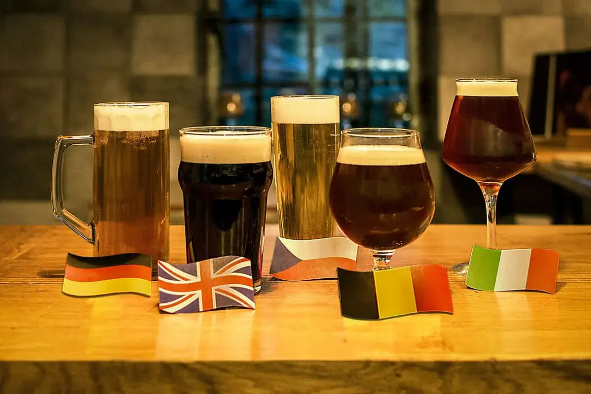 Cinq bi&egrave;res aux couleurs vari&eacute;es, de la blonde &agrave; la brune, align&eacute;es avec des drapeaux europ&eacute;ens.